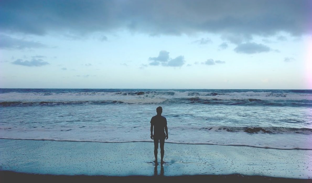 A man looking out across an ocean at dusk