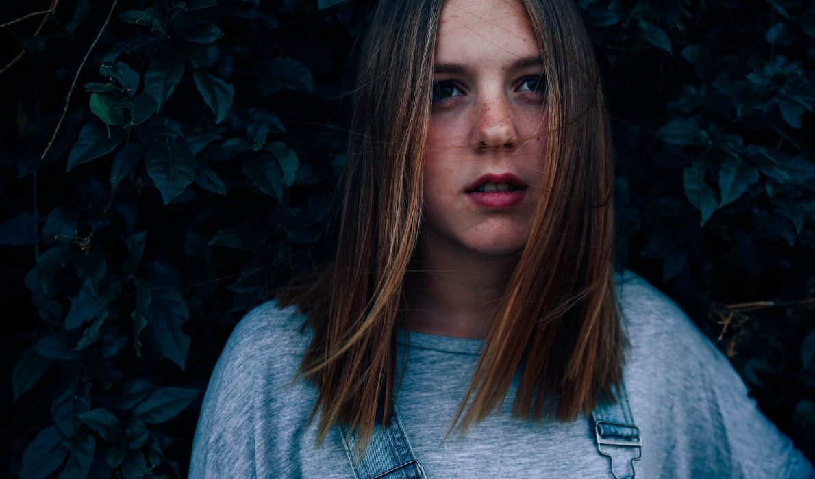 Young woman in overalls looking up at the sky
