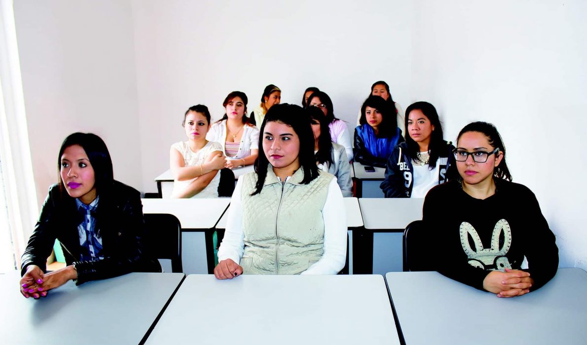 Room of young women sitting at school desks