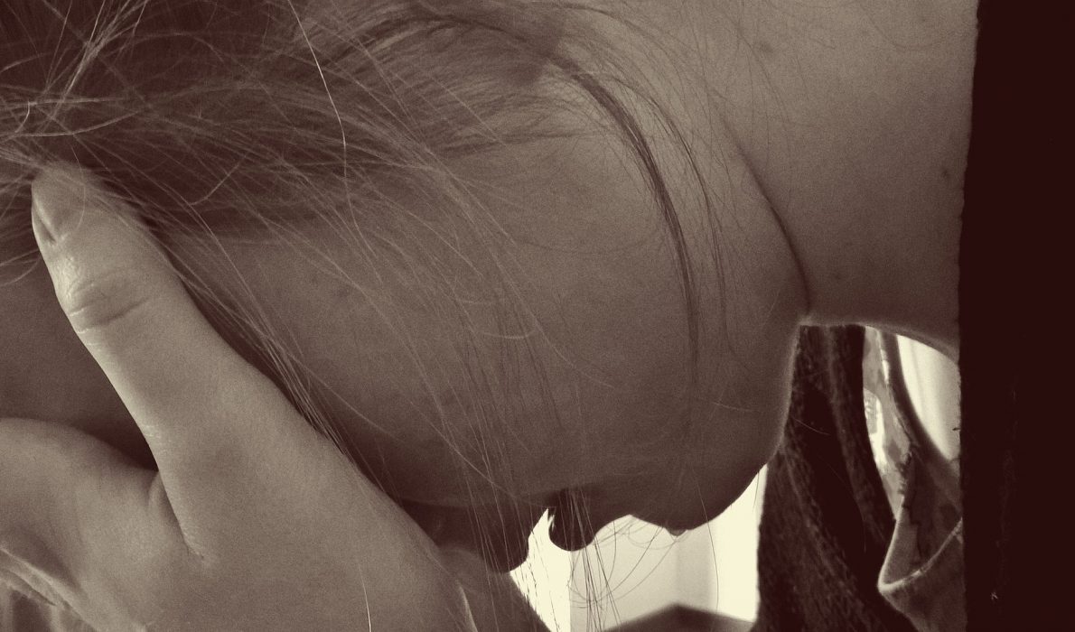 Young woman leaning forward with her forehead in her hands