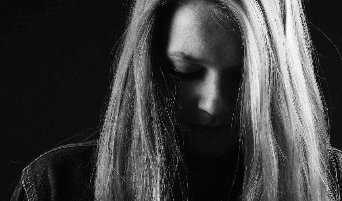 Blonde woman looking down with her hair covering her face